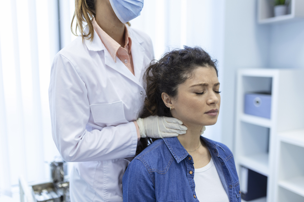 Endocrinologist examining throat of young woman in clinic. Women with thyroid gland test . Endocrinology, hormones and treatment. Inflammation of the sore throat thyroid